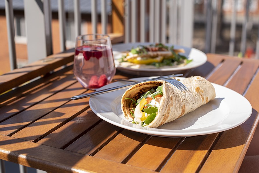 Valmis t�ytetty wrap ja lasillinen mehua auringossa parvekep�yd�ll�.