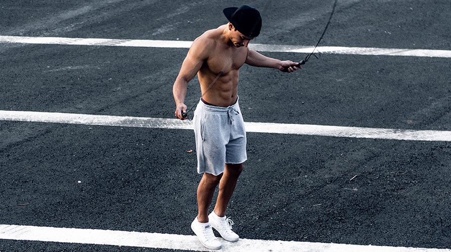 Mies hyppii hyppynarulla ilman paitaa. Mies hyppii hyppynarulla ilman paitaa.