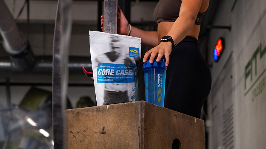 Nainen koskee sheikkeriä, joka on Core Casein -pussin vieressä puisen boxin päällä kuntosalilla. Nainen koskee sheikkeriä, joka on Core Casein -pussin vieressä puisen boxin päällä kuntosalilla.