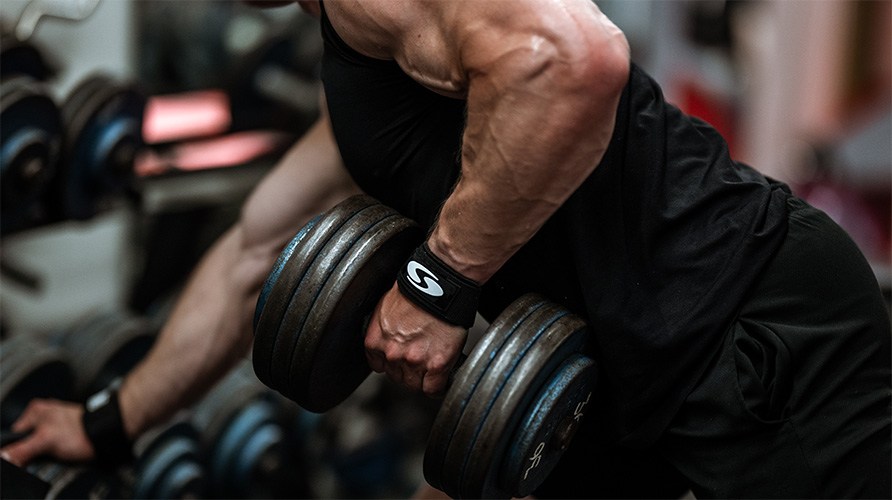 Lihaksikas mies treenaa ksilihaksia ksipainolla ranteessa hand wrap.