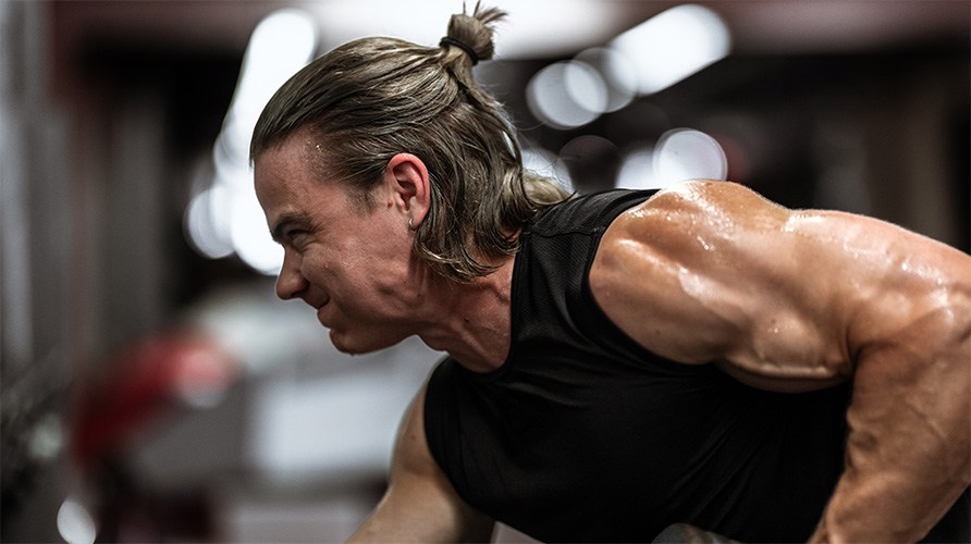 Mies ponnistelee treenatessaan. 