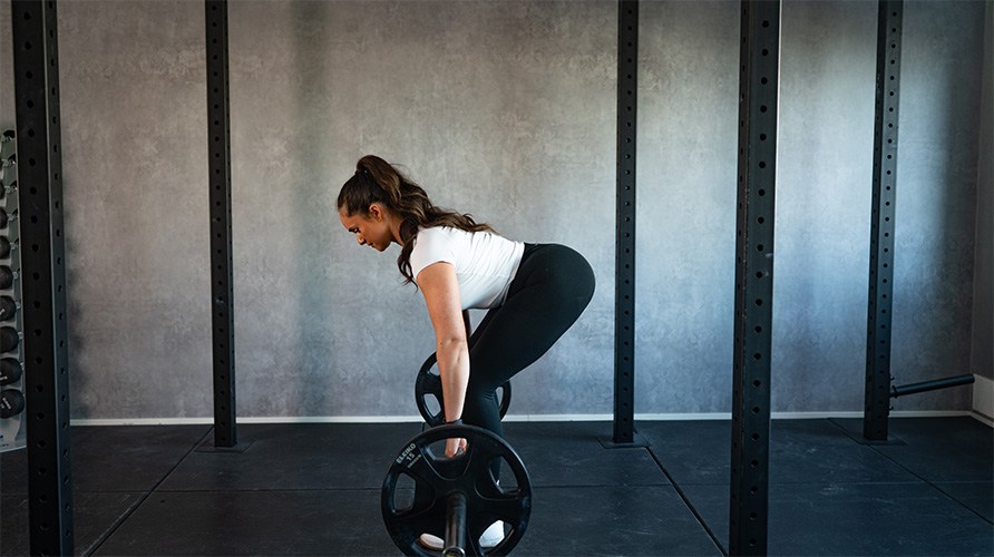 Nainen suorittaa romanialaisia maastavetoja, tss loppuasennossa.