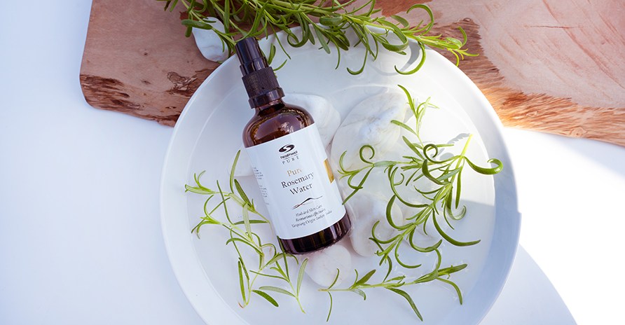 Healhtwell PURE Rosmariinivesi valkoisessa kulhossa rosmariininoksien ja valkoisten kivien kanssa.