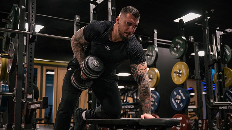 Mies suorittaa harjoitusta, k�sipainosoutu.