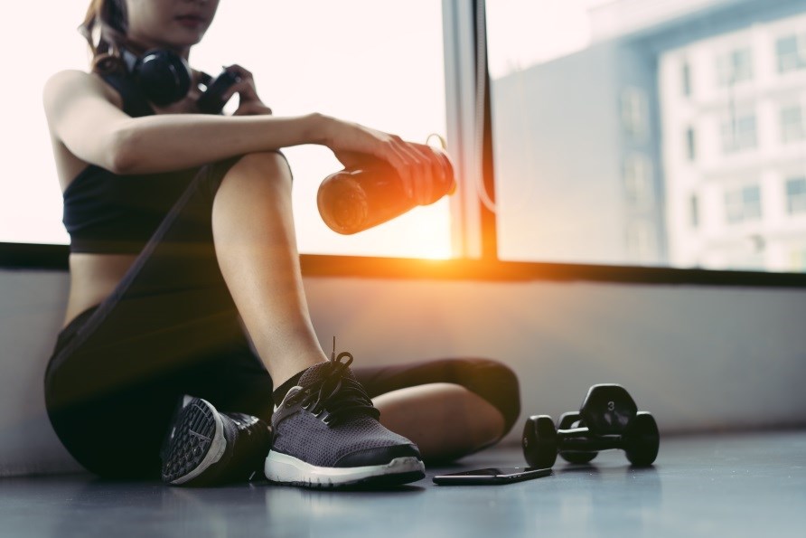 Tyttö istuu lattialla kuntosalissa Tyttö istuu lattialla kuntosalissa