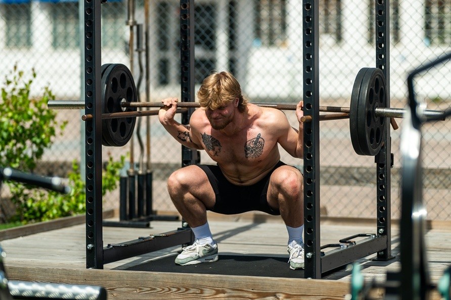 Mies suorittaa kyykkyharjoituksen ulkona.